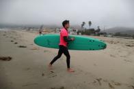 A surf instructor carries a Doyle surfboard in Malibu