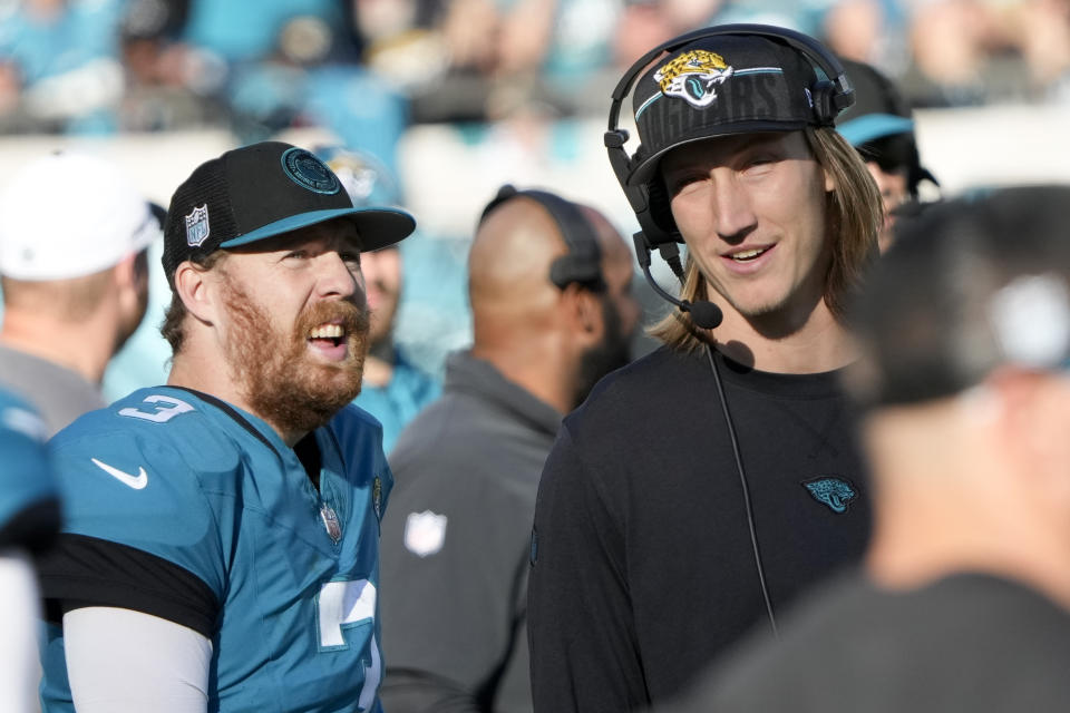 Jacksonville Jaguars quarterback C.J. Beathard talks with injured quarterback Trevor Lawrence during the second half of an NFL football game against the Carolina Panthers Sunday, Dec. 31, 2023, in Jacksonville, Fla. (AP Photo/John Raoux)