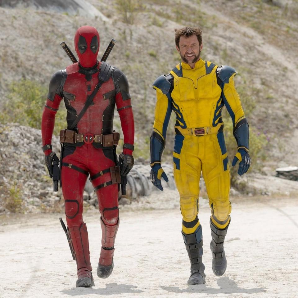 deadpool and wolverine walk along a sandy road