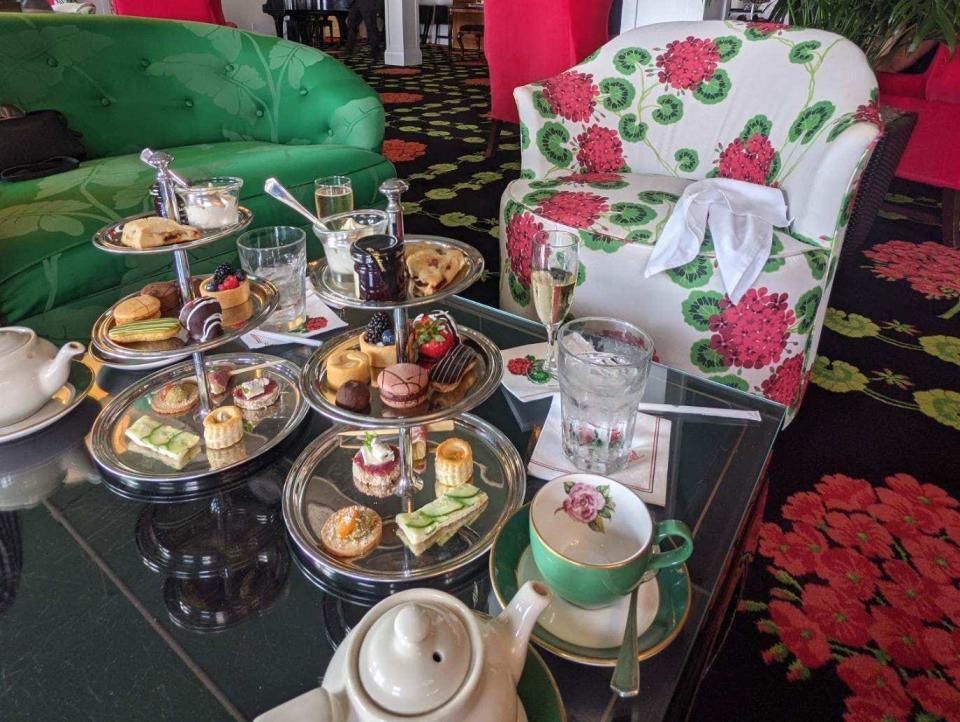 Trays of desserts and pots of tea at the hotel, which has floral couches and brightly-colored furniture.