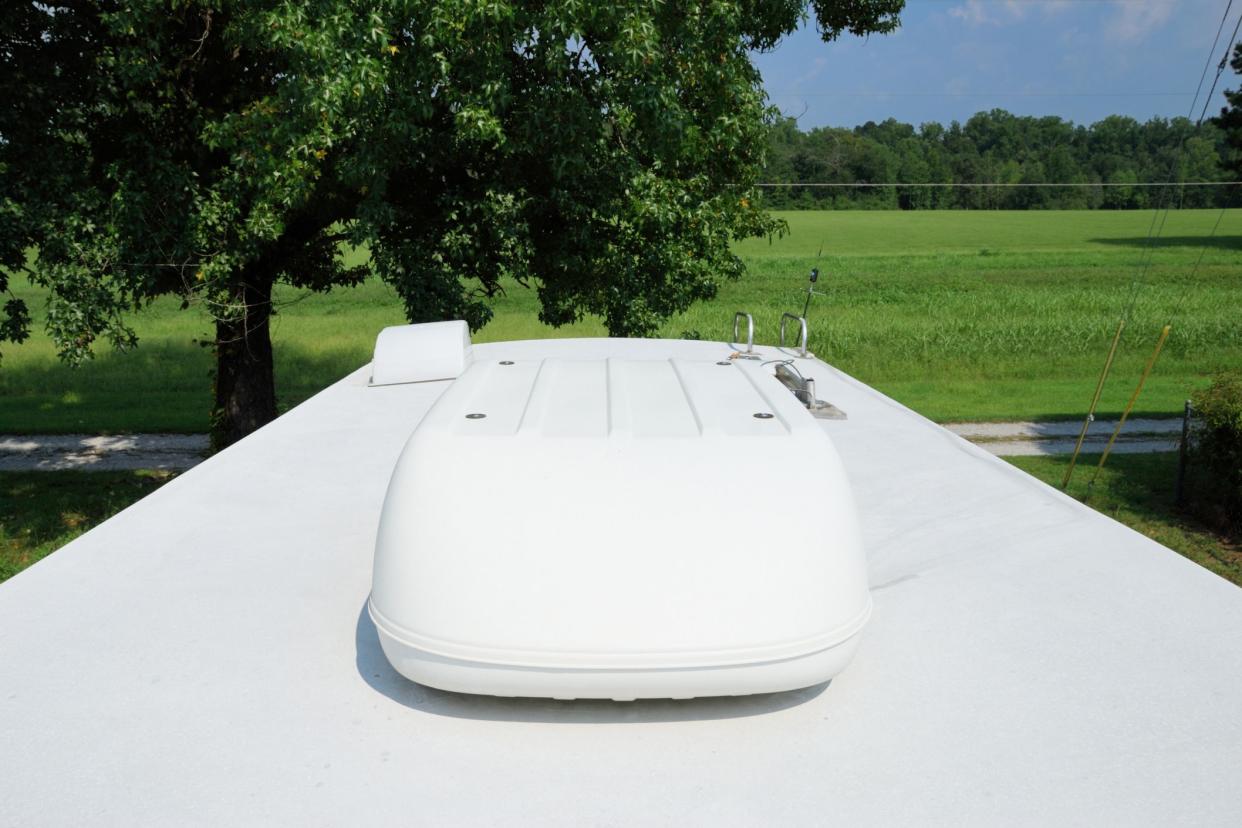 ac unit on rv roof, grass and tree in background