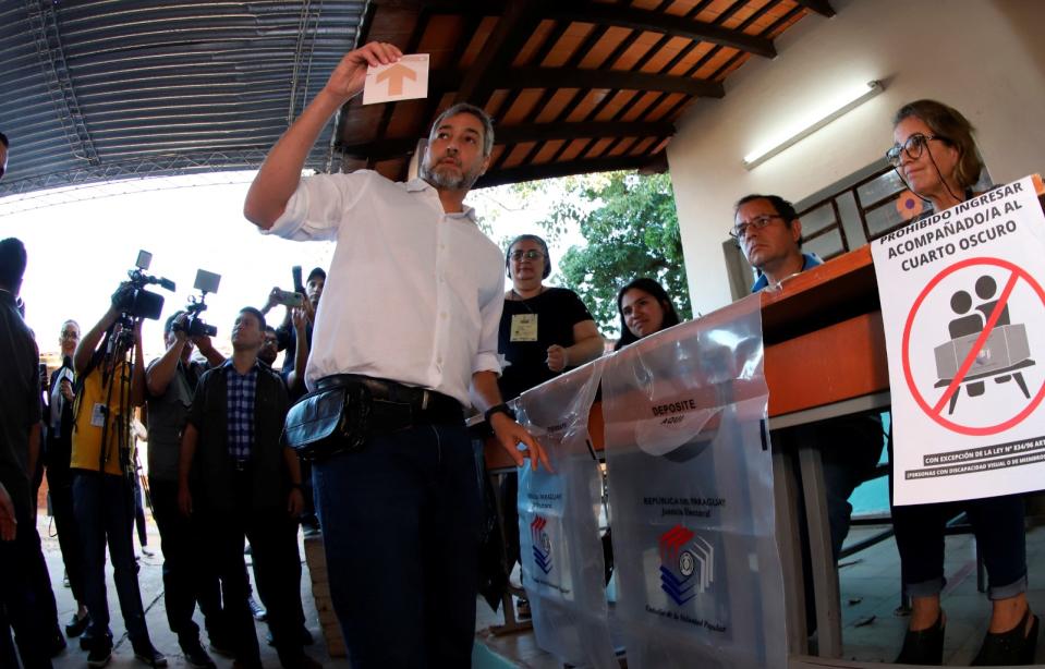2023年4月30日，巴拉圭總統阿布鐸（Mario Abdo Benitez）展示電子投票機紙卡。右側工作人員桌前貼著禁止陪同投票的標示，但巴拉圭中選會先前曾表示在特定情況下可以陪同操作。路透社
