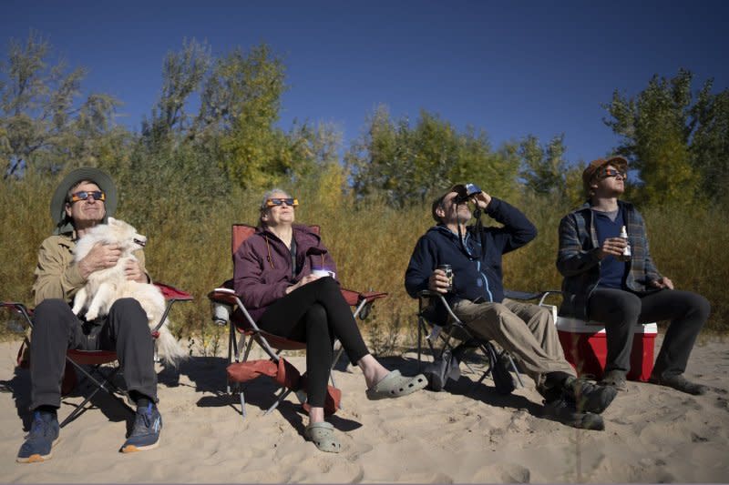 From left to right, Steven, Ellen, Tim and Simon Viavant watch as the moon covers the sun during an annular "Ring of Fire" solar eclipse near Bluff, Utah, in October. File Photo by Bob Strong/UPI