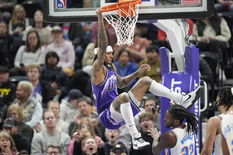 Utah Jazz guard Jordan Clarkson, left, hangs off the basket after dunking on Oklahoma City Thunder guard Cason Wallace (22) during the first half of an NBA basketball game Tuesday, Feb. 6, 2024, in Salt Lake City. (AP Photo/Rick Bowmer)