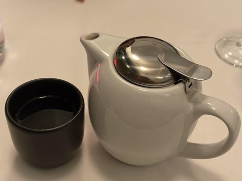 white tea kettle on table next to black cup