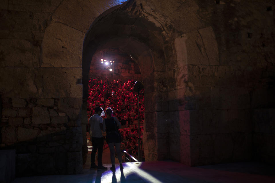 A Steward wearing a plastic visor stands at a gate of the Odeon of Herodes Atticus in Athens, during a concert on Wednesday, July 15, 2020. Greek Culture Ministry allowed the ancient theaters of Epidaurus in southern Greece and Herodes Atticus in Athens to host performances under strict safety guidelines due the COVID-19 pandemic.(AP Photo/Petros Giannakouris)