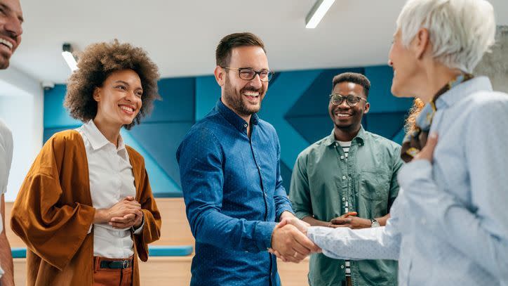 Employees shake hands with a coworker who is retiring.