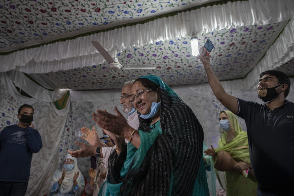 Kashmiri couple, center, clap as they celebrate henna ceremony of their son's wedding Haseeb Mushtaq, on the outskirts of Srinagar, Indian controlled Kashmir, Sunday, Sept. 13, 2020. The coronavirus pandemic has changed the way people celebrate weddings in Kashmir. The traditional week-long feasting , elaborate rituals and huge gatherings have given way to muted ceremonies with a limited number of close relatives attending. With restrictions in place and many weddings cancelled, the traditional wedding chefs have little or no work. The virus has drastically impacted the life and businesses in the region. (AP Photo/ Dar Yasin)