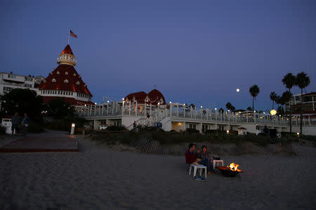 A couple sit by a fire on the beach as tech nerds and stock traders gather for StockTwits annual Stocktoberfest on the beach at Hotel Del in Coronado, California, U.S. October 14, 2016. Picture taken October 14, 2016. REUTERS/Mike Blake
