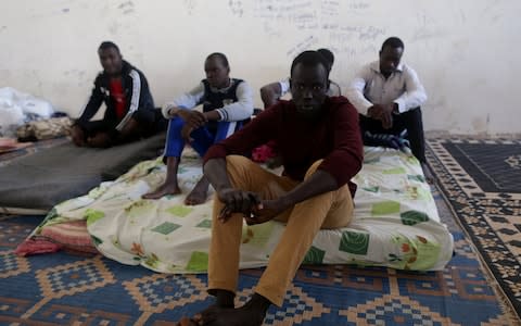 Migrants sit in a detention centre run by the interior ministry of Libya's eastern-based government, in Benghazi - Credit: Reuters