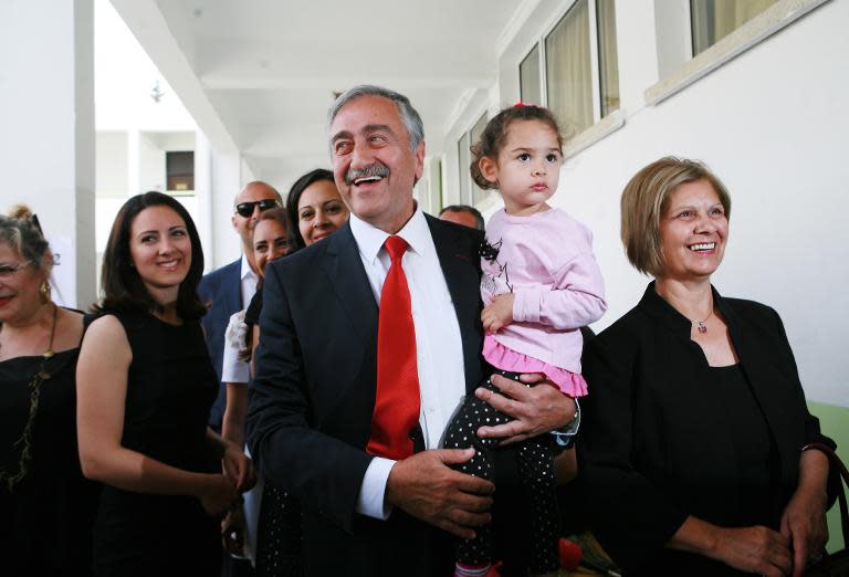 Turkish Cypriot independant candidate for the presidential elections, Mustafa Akinci, and his wife Meral (R) arrive with their family at a polling station on April 26, 2015 in the northern part of Nicosia