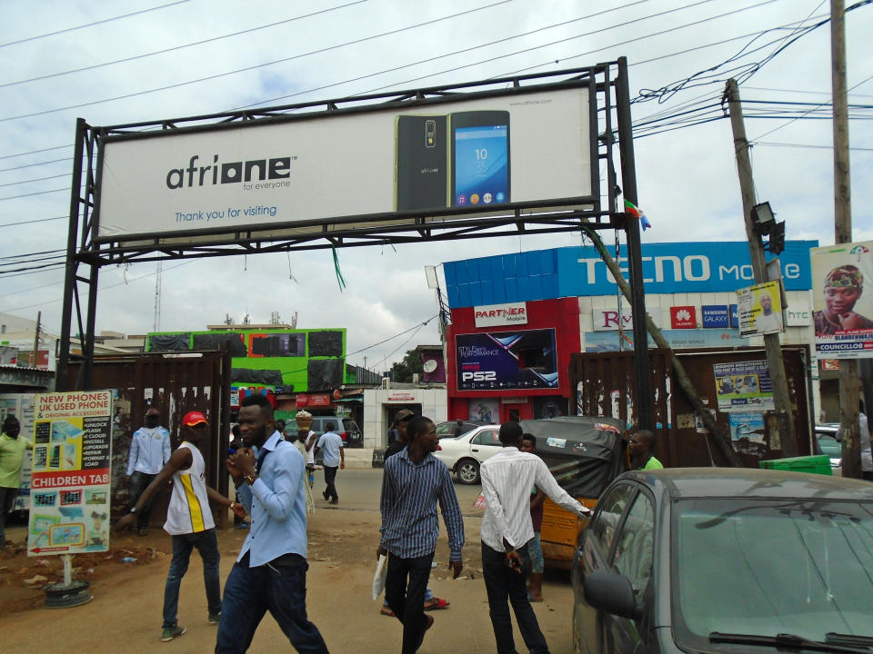 An AfriOne billboard sits above a gate to Computer Village in Lagos, competing with a Tecno-branded building façade across the street. (Photo: Armin Rosen for Yahoo News)