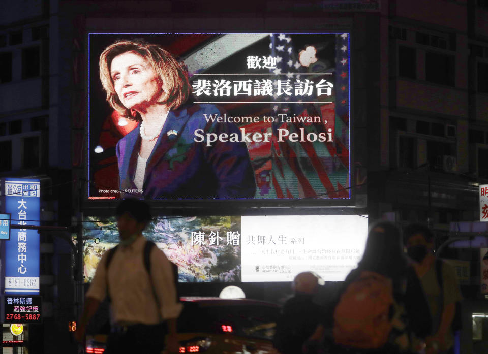 People walk past a billboard welcoming U.S. House Speaker Nancy Pelosi, in Taipei, Taiwan, Tuesday, Aug 2, 2022. Pelosi has arrived in Taiwan and becomes the highest-ranking American official in 25 years to visit the self-ruled island claimed by China, which quickly announced that it would conduct military maneuvers in retaliation for her presence. (AP Photo/Chiang Ying-ying)