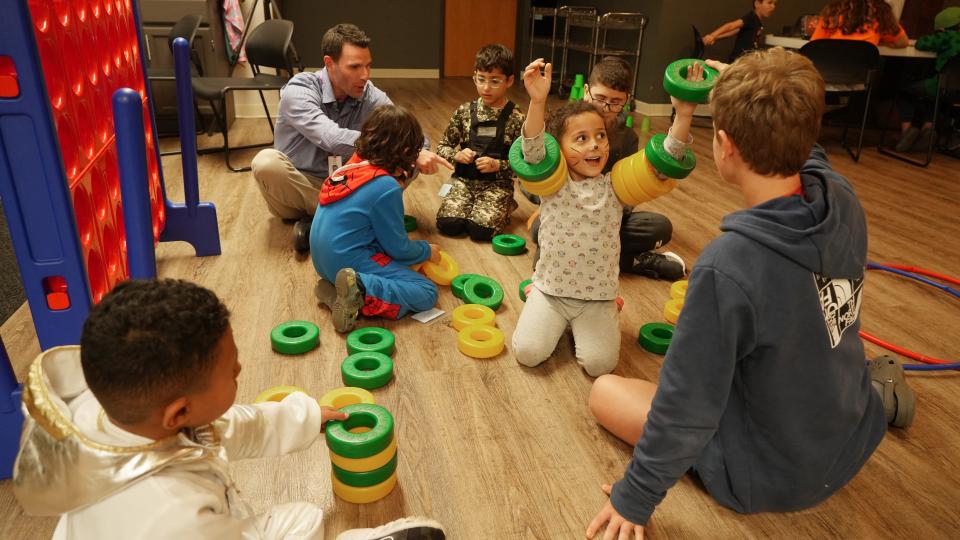 While their parents are upstairs learning English, children learn language skills while playing with volunteers at a three-generation English as a Second Language program run by Festa, a local nonprofit group. At top left, Nick Knebel plays with children while his son, Elliott, 13, plays with Celine Khadrah. Festa has two sites in Greater Columbus; this one is in Indian Run United Methodist Church in Dublin.