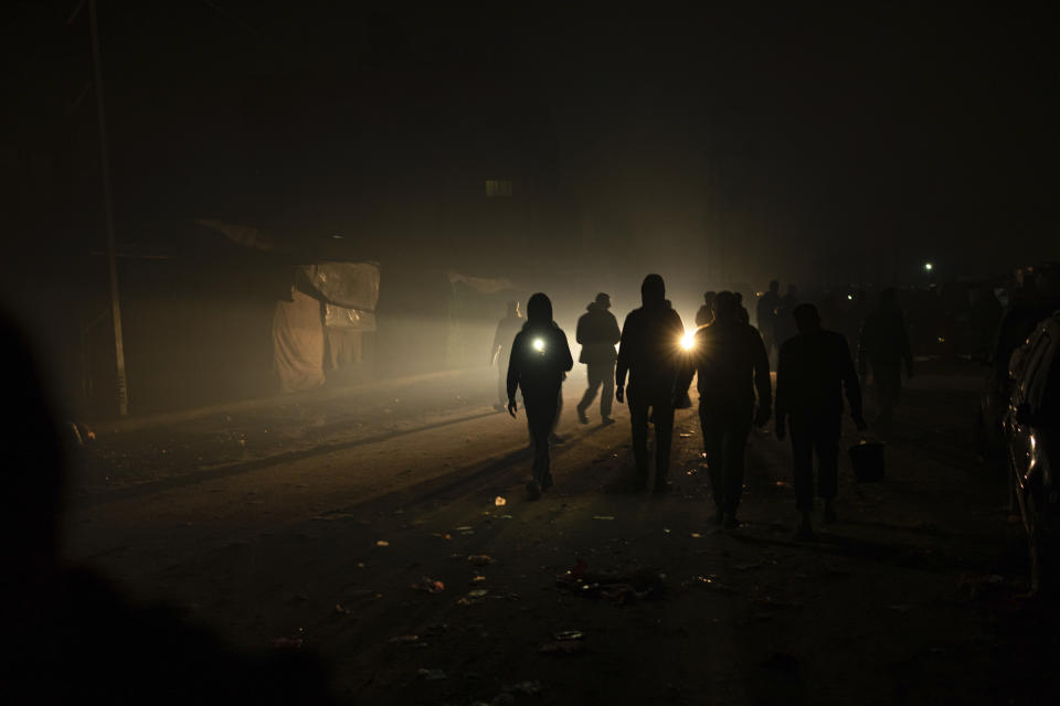 Palestinians displaced by the Israeli bombardment of the Gaza Strip walk in the dark with flashlights at the makeshift tent camp in the Muwasi area on Sunday, Dec. 31, 2023. Israel has encouraged Palestinians to move to Muwasi, telling them they will be safe from bombing. (AP Photo/Fatima Shbair)