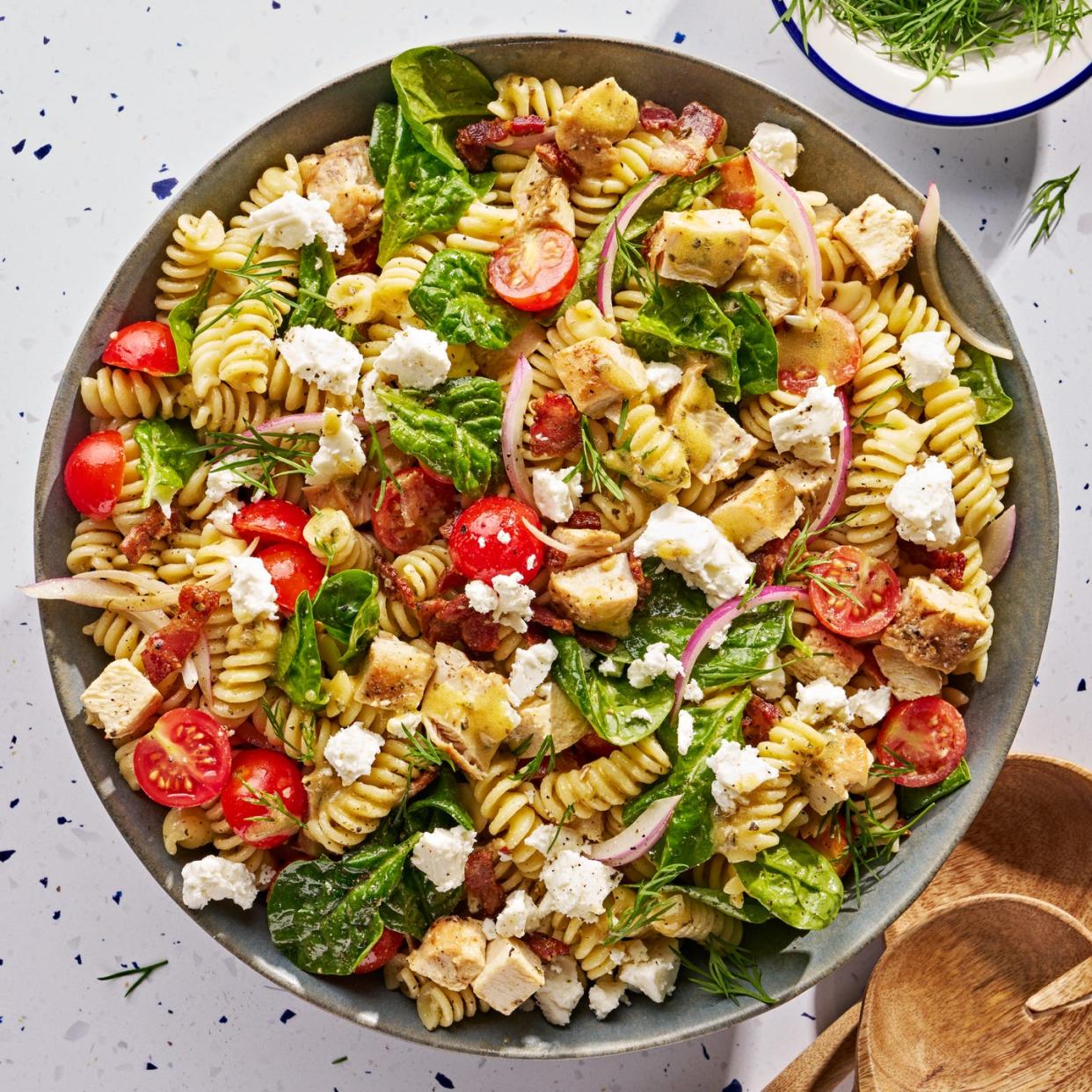 chicken pasta salad with tomatoes, sliced red onion, feta, basil, and bacon