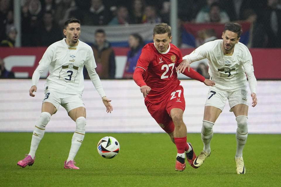 Russia's Ivan Oblyakov, centre, challenges for the ball with Serbia's Filip Mladenovic, left, and Serbia's Mijat Gacinovic during an international friendly soccer match between Russia and Serbia at the Central Dynamo Stadium of Lev Yashin in Moscow, Russia, Thursday, March 21, 2024. (AP Photo/Alexander Zemlianichenko)
