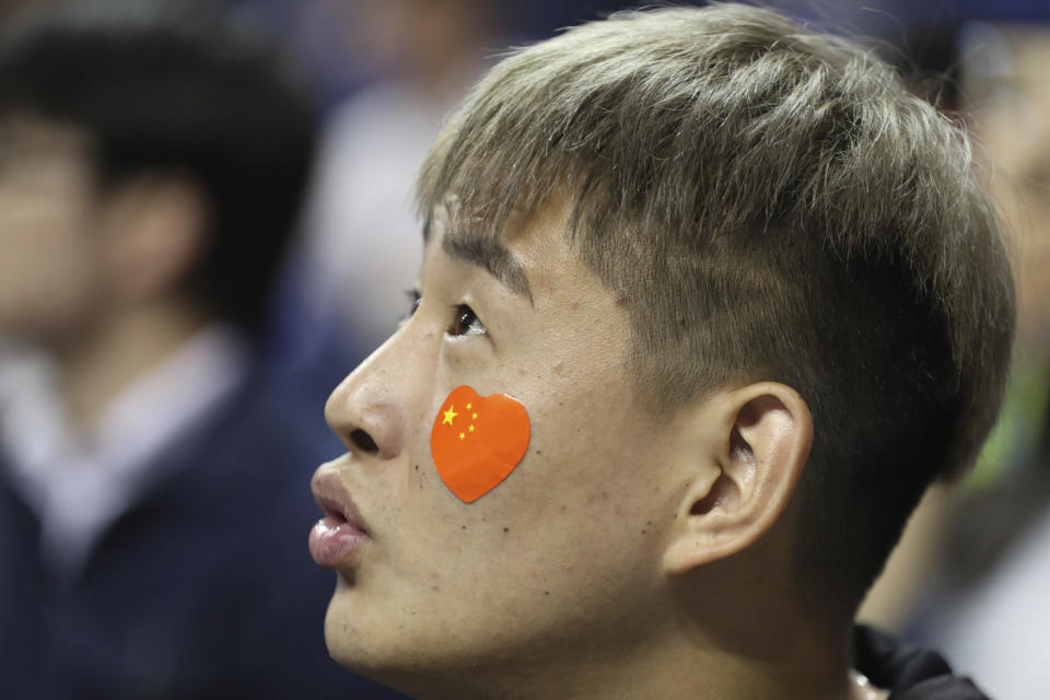 A fan with a heart-shaped Chinese national flag sticker on his face watches a preseason NBA basketball game between the Brooklyn Nets and Los Angeles Lakers at the Mercedes Benz Arena in Shanghai, China, Thursday, Oct. 10, 2019. (AP Photo)