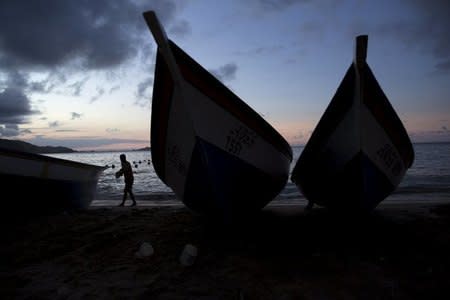 A man walks past wooden boats in the bay of Rio Caribe a town near caribbean islands, in the eastern state of Sucre, Venezuela October 29, 2015. REUTERS/Carlos Garcia Rawlins