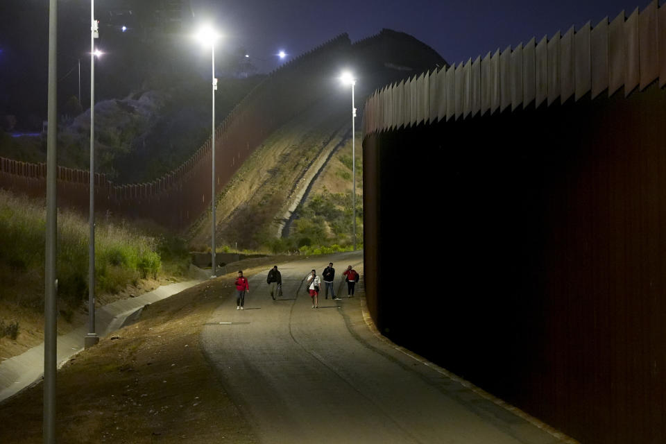 Jordanian migrants walk along the border walls separating Tijuana, Mexico, and San Diego, to apply for asylum with U.S authorities Tuesday, May 7, 2024, in San Diego. San Diego became the busiest corridor for illegal crossings in April, according to U.S. figures, the fifth region to hold that title in two years in a sign of how quickly migration routes are changing. (AP Photo/Ryan Sun)