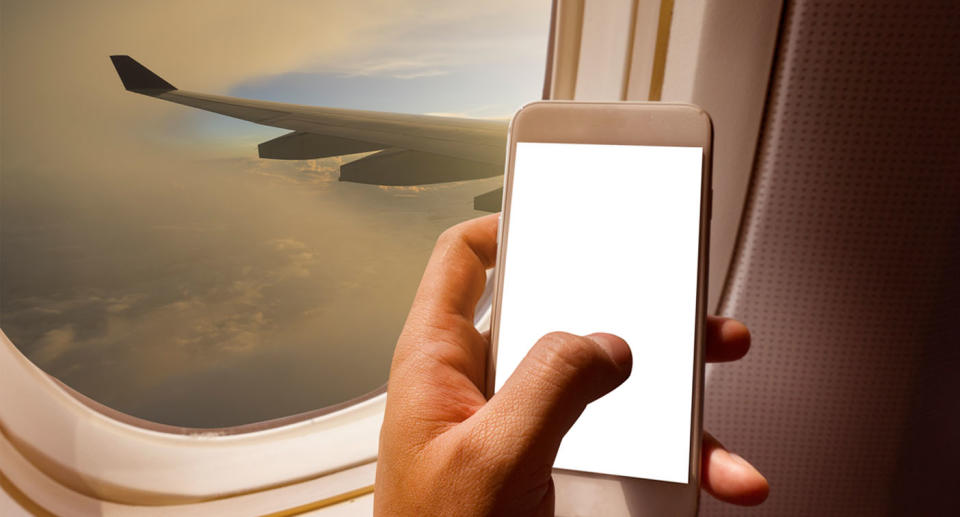 Plane passenger in window seat holding phone