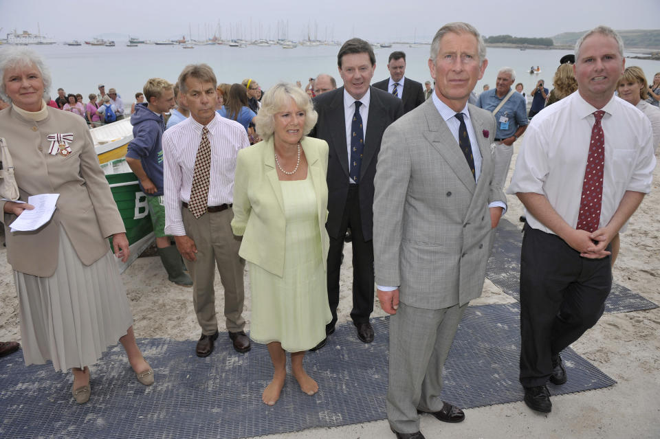 The Prince of Wales with The Duchess of Cornwall, who has taken her shoes off, look at information about the heritage of the boat club during their visit to the Gig Boat Club at Porthmellon, St Mary's, Isles of Scilly.   (Photo by Ben Birchall - PA Images/PA Images via Getty Images)