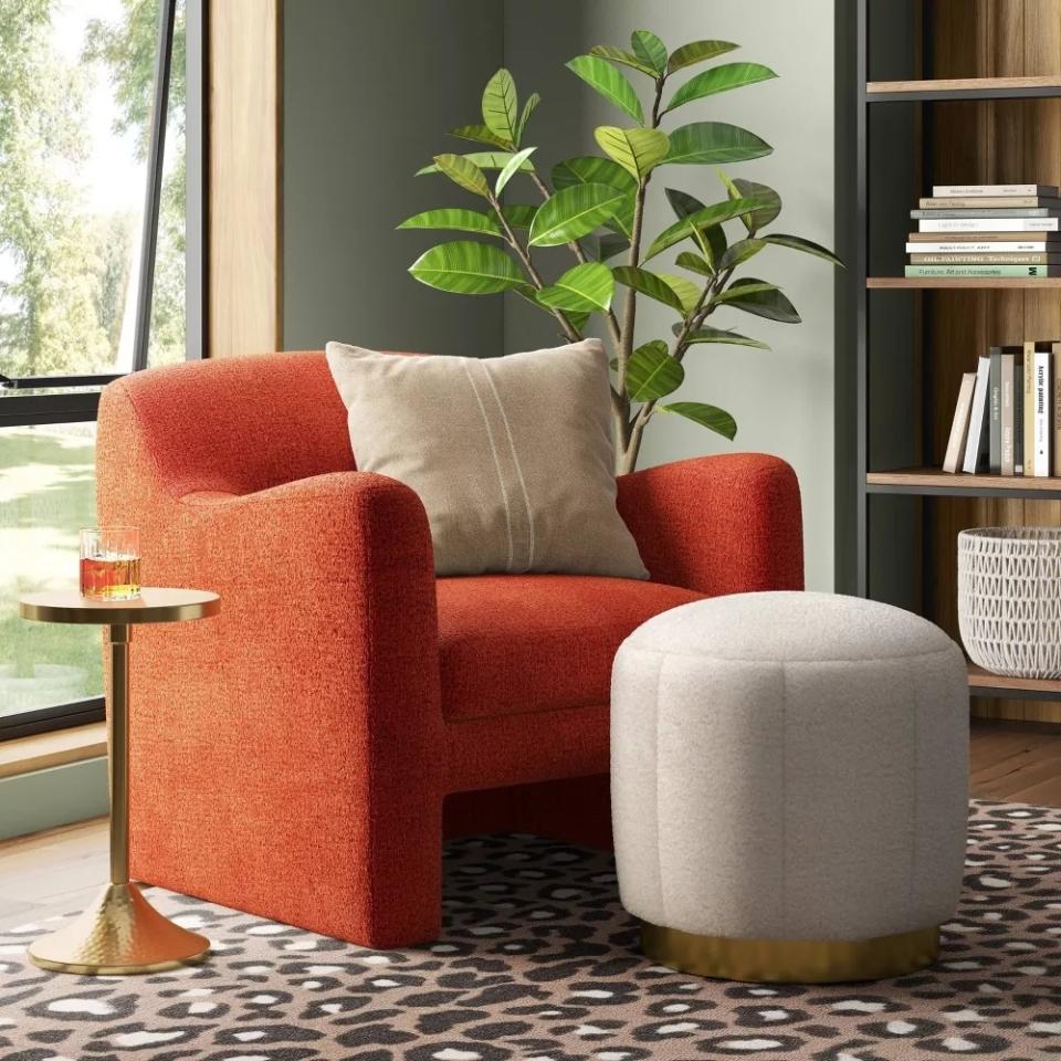 the tufted ottoman with a brass base in a living room