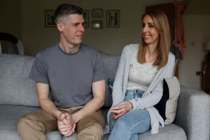 Laura sat on the sofa with her husband Duncan, the couple are looking at each other smiling