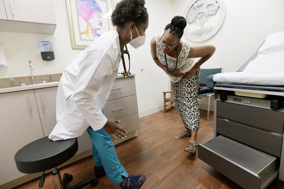 Registered nurse practitioner and midwife Jamie Neal works patient Jacqueline Fletcher through some stretching exercises to help with hip pain at Life Tree Women Care.