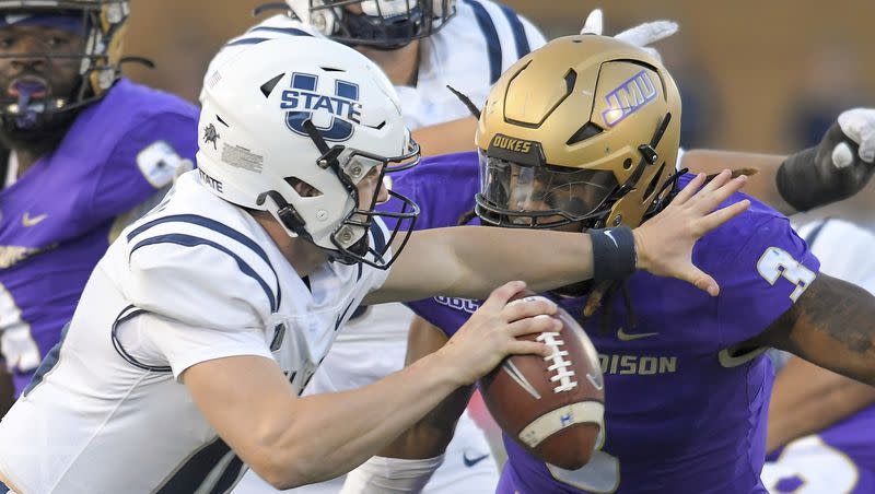 Utah State quarterback McCae Hillstead, front left, tries to scramble away from James Madison defensive lineman Mikail Kamara (3) during the first half of an NCAA college football game Saturday, Sept. 23, 2023, in Logan, Utah. 