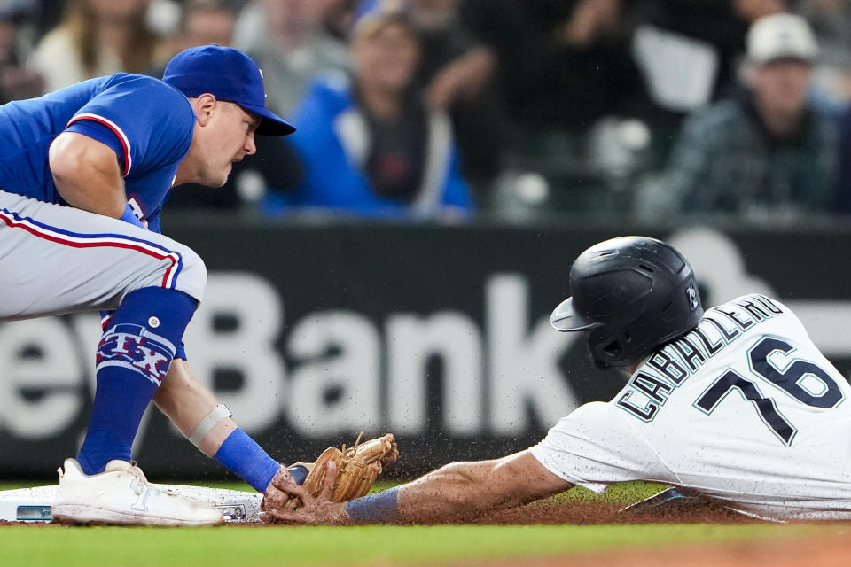 Texas Rangers third baseman Josh Jung, left, tags out Seattle Mariners' Jose Caballero, who tried to advance to third on a single by J.P. Crawford during the fifth inning of a baseball game Thursday, Sept. 28, 2023, in Seattle. (AP Photo/Lindsey Wasson)