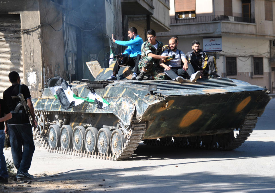 Syrian army soldiers and rebels sit on the top of an armored personnel carrier shortly after the Syrian soldiers defected and joined the rebels, in Khaldiyeh district, in Homs province, central Syria, Saturday May 12, 2012. Syria's uprising started in March 2011 with mostly peaceful protests inspired by successful revolts elsewhere calling for political reform. The Syrian government responded with a brutal crackdown, prompting many in the opposition to take up arms to defend themselves and attack government troops. (AP Photo/Fadi Zaidan)