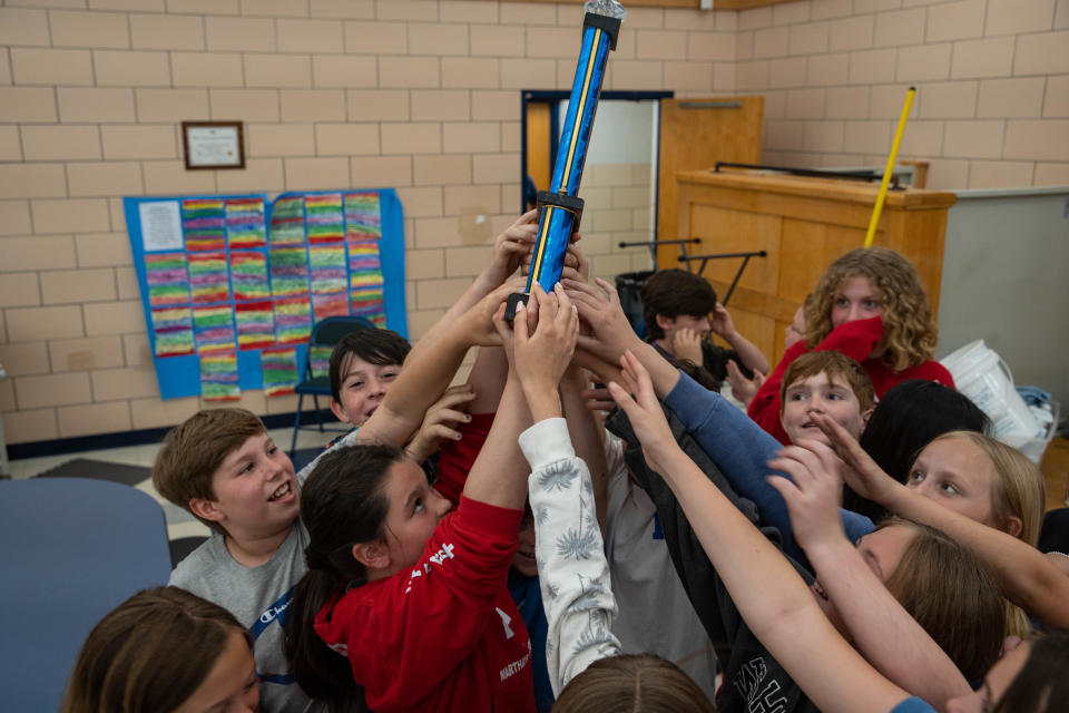 Student of Gretchen Abbott's class raise the Vinal Book Bee trophy high in the air on Friday, May 27, 2022.