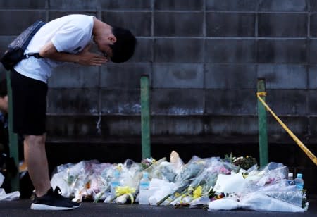 A man prays outside the Kyoto Animation building which was torched by arson attack, in Kyoto