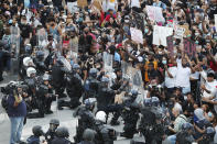 In a show of peace and solidarity, law enforcement officials with riot shields kneel in front of protesters Monday, June 1, 2020, during a fourth day of protests over the death of George Floyd in Minneapolis. (Curtis Compton/Atlanta Journal-Constitution via AP)