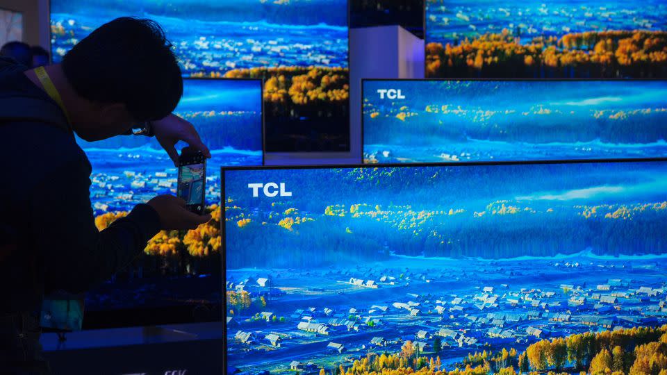 A man photographs TCL 4K UHD TVs during the 2017 Consumer Electronic Show (CES) at the Las Vegas Convention Center in Las Vegas, Nevada, January 5, 2017. - David McNew/AFP/Getty Images