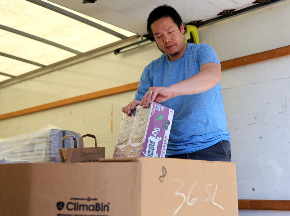 Norm Chaichankanchang, warehouse manager for the Pet Food Pantry of Oklahoma, opens packs of water in the nonprofit's van during a recent pet food giveaway event.