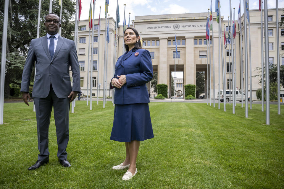 Rwandan Foreign Minister Vincent Biruta, left, and Britain's Home Secretary Priti Patel, right, speaks during an interview with the Associated Press at the European headquarters of the United Nations in Geneva, Switzerland, Thursday, May 19, 2022. (Martial Trezzini/Keystone via AP)