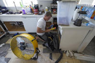 Jordan Cromer cleans water-logged items at his home, Tuesday, Oct. 4, 2022, in North Port, Fla. Residents along Florida's west coast are cleaning up damage after Hurricane Ian make landfall the week before. (AP Photo/Chris O'Meara)