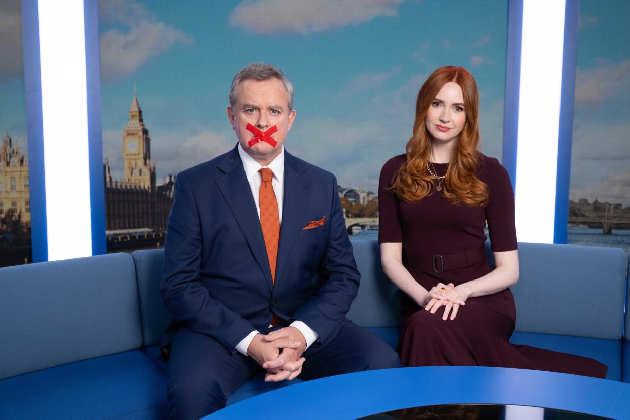 Hugh Bonneville and Karen Gillan sit on a blue sofa in a scene from Douglas is Cancelled