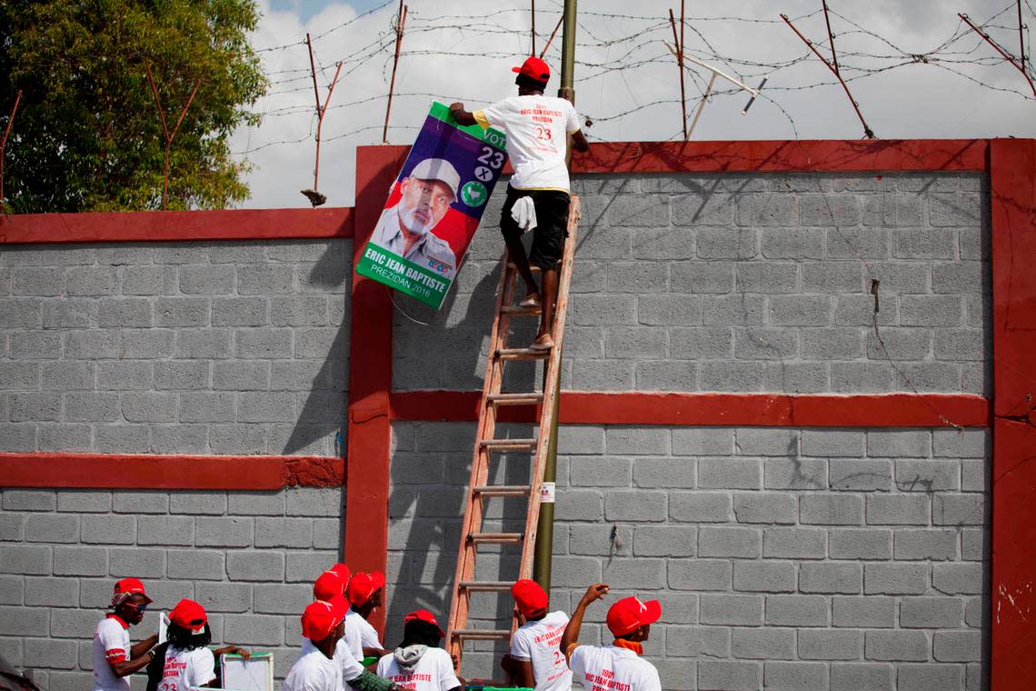 In this Oct. 11, 2015 photo, campaigners hang a poster of presidential candidate Eric Jean-Baptiste, of the MAS political party, in Carrefour, Haiti. This year’s unprecedented three rounds of balloting will pick Haiti’s next president, two-thirds of the Senate, the entire 119-member Chamber of Deputies and numerous local offices.