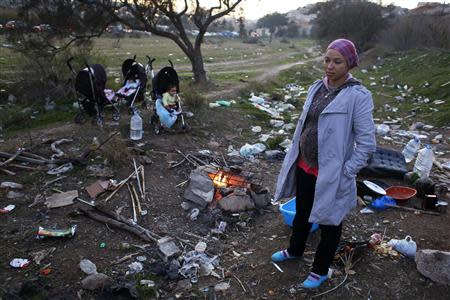 24-year-old Algerian Khedidja Azzouz, who is pregnant and homeless stands near a fire in a littered landscape in Spain's north African enclave Melilla December 7, 2013. REUTERS/Juan Medina