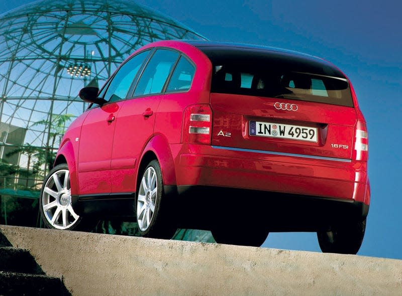 A red Audi A2 from the rear in front of a big glass dome of some sort.