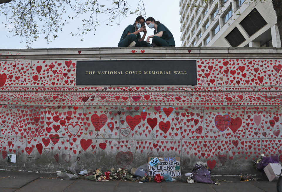 FILE - Nurses from the nearby St Thomas' hospital sit atop the National Covid Memorial Wall in London, April 27, 2021. The pandemic is again roaring across parts of Western Europe, a prosperous region with relatively high vaccination rates and good health care systems but where lockdown measures to rein in the virus are largely a thing of the past. The U.K. had Europe’s highest infection rates for months after the government lifted remaining restrictions on social and economic life in mid-July — though cases have gone up and down since then, and now appear to be falling. (AP Photo/Frank Augstein)
