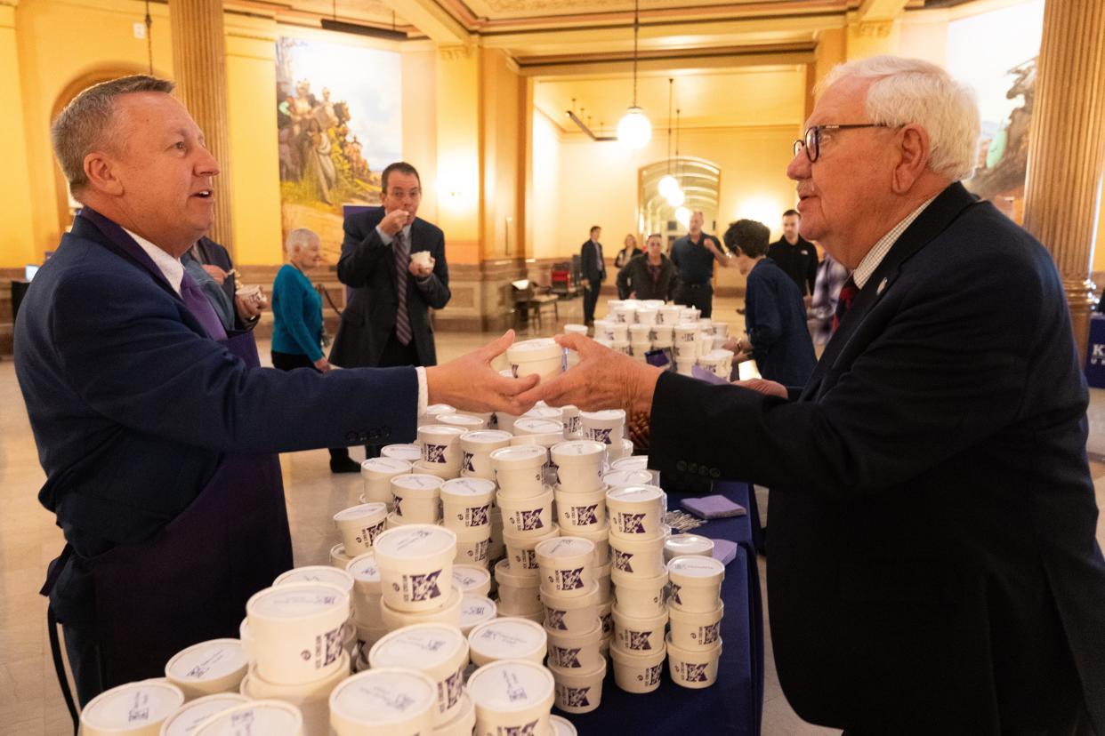 Kansas State University president Richard Linton, left, offers Sen. Rick Wilborn, R-McPherson, right, a sample of the new Call Hall Ice Cream flavor, 'Cherry Choco Crunch', Wednesday at the Statehouse.