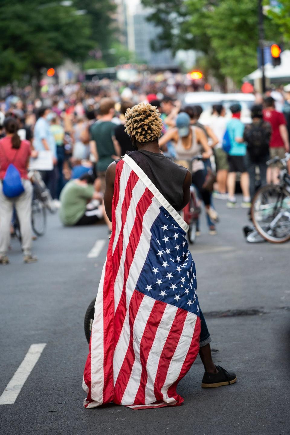 A man draped in the U.S. flag sits on a motorized bicycle near the White House during June 3, 2020, protests over the death of George Floyd. <a href="https://www.gettyimages.com/detail/news-photo/man-draped-in-the-us-flag-sits-on-his-motorized-bicycle-news-photo/1217490160?adppopup=true%20ALT%20TEXT:%20A%20man%20draped%20in%20the%20US%20flag," rel="nofollow noopener" target="_blank" data-ylk="slk:Roberto Schmidt/AFP via Getty Images;elm:context_link;itc:0;sec:content-canvas" class="link ">Roberto Schmidt/AFP via Getty Images</a>