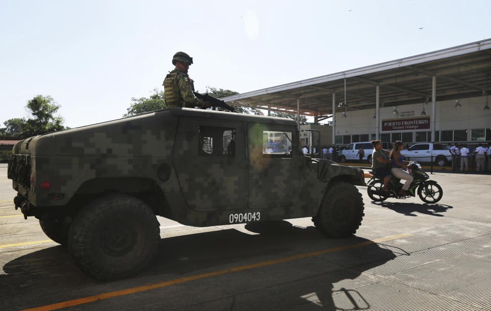 A Mexican army soldier watches National Guards hold a ceremony at a border crossing in Ciudad Hidalgo, Mexico, Friday, Jan. 17, 2020 as they deploy along southern border with Guatemala. United States officials are crediting tough measures taken over the past year and cooperation from regional governments for sharply reducing the number of Central American migrants who responded to a call for a new caravan. (AP Photo/Marco Ugarte)