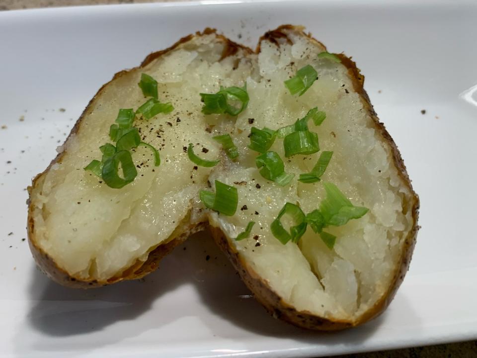 Baked potato split in half and garnished with pepper and green onions