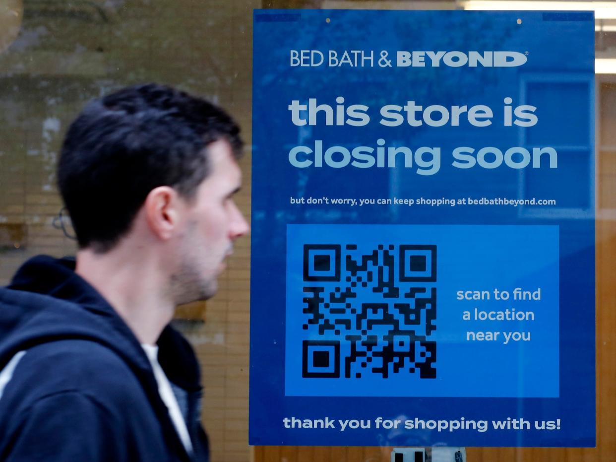 Man walks past Bed Bath & Beyond store with store closing sign in window