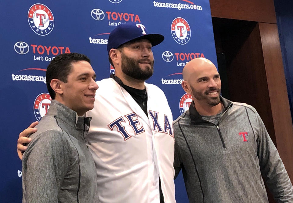 Newly signed Texas Rangers pitcher, Lance Lynn, center, wears his new team jersey as he poses for photos with general manager Jon Daniels, left, and manager Chris Woodward, right, after a news conference where Lynn was officially introduced in Arlington, Texas, Tuesday, Dec. 18, 2018. (AP Photo/Stephen Hawkins)